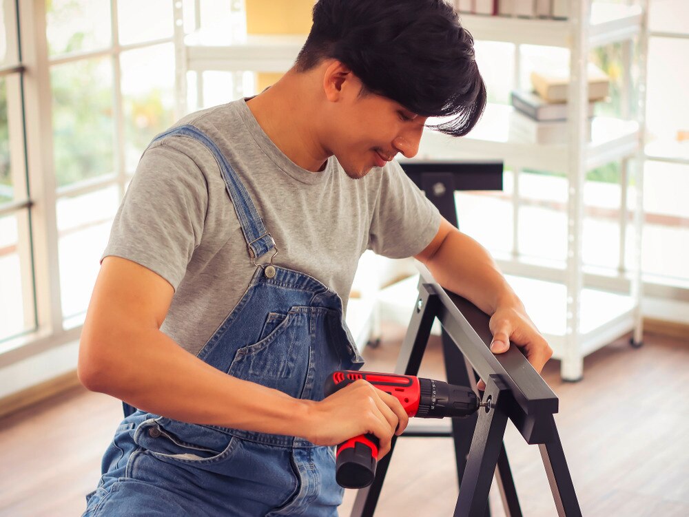 Man using an electric screwdriver to assemble furniture