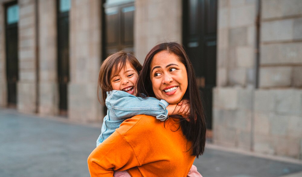 Asian woman giving her daughter a piggyback ride.