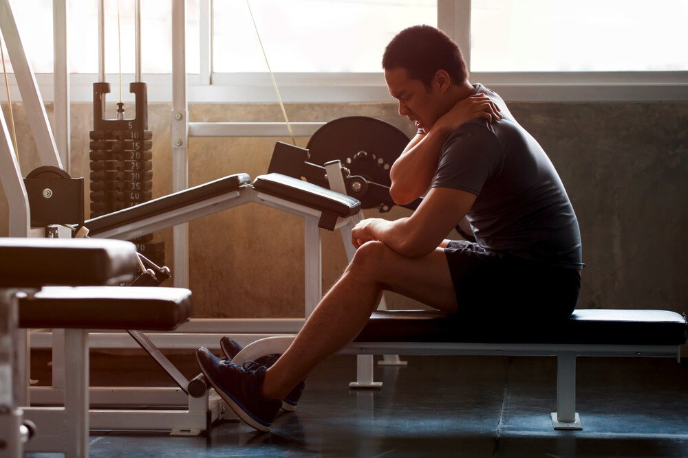 Man touching his shoulder in pain while exercising at the gym.