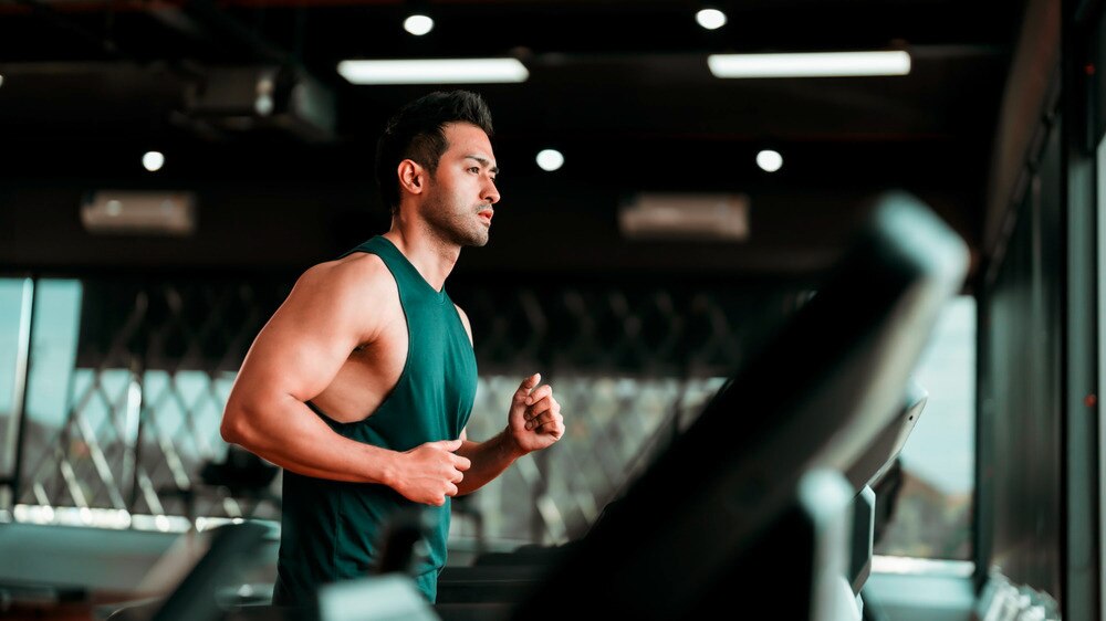 Muscular man running on treadmill.