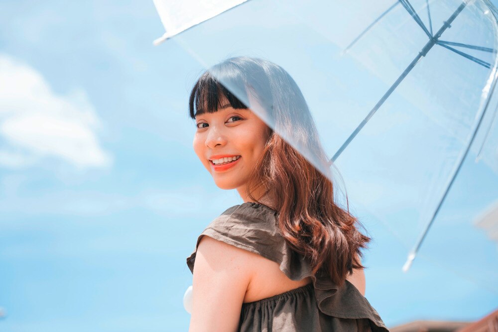 A portrait of smiling woman holding an umbrella.