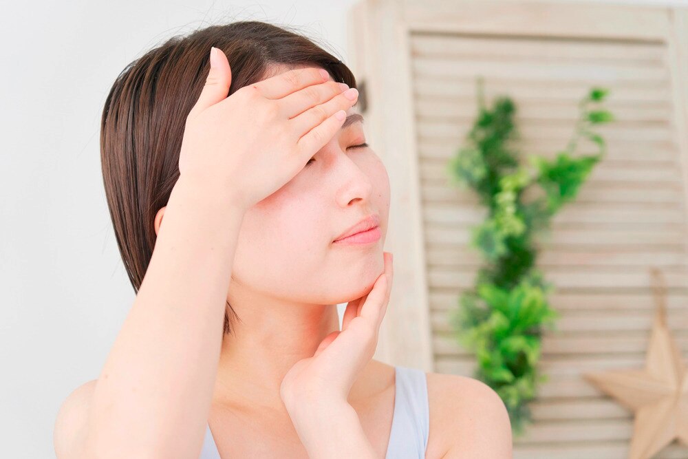 Woman massaging sunscreen onto her face.