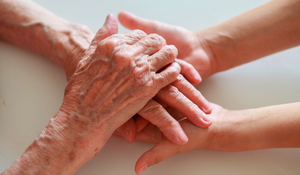 A portrait of an old woman’s hand holding a young person’s hand.