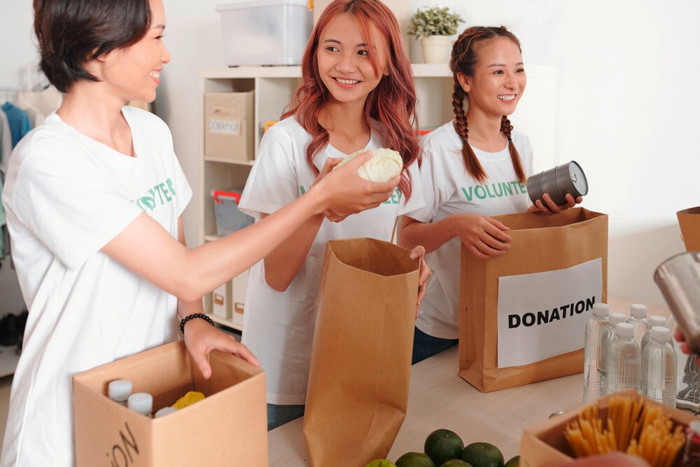 A portrait of female volunteers accepting food donations. 