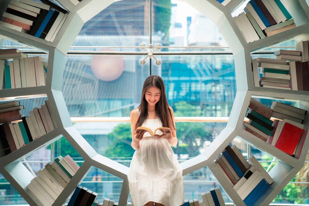 Woman reading a book inside a library.