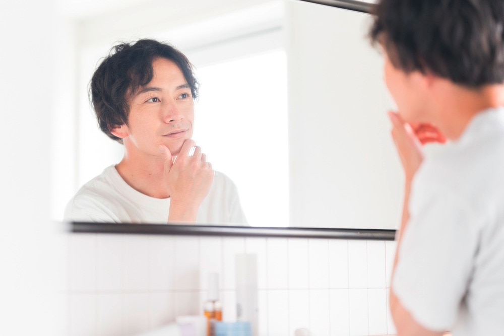 Man checking his face and hair in the mirror.