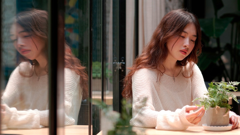 Asian woman with long wavy hair sitting in a café.