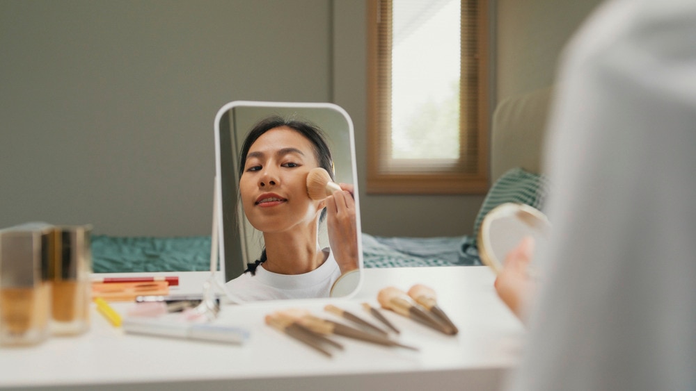 Woman applying powder on her face.