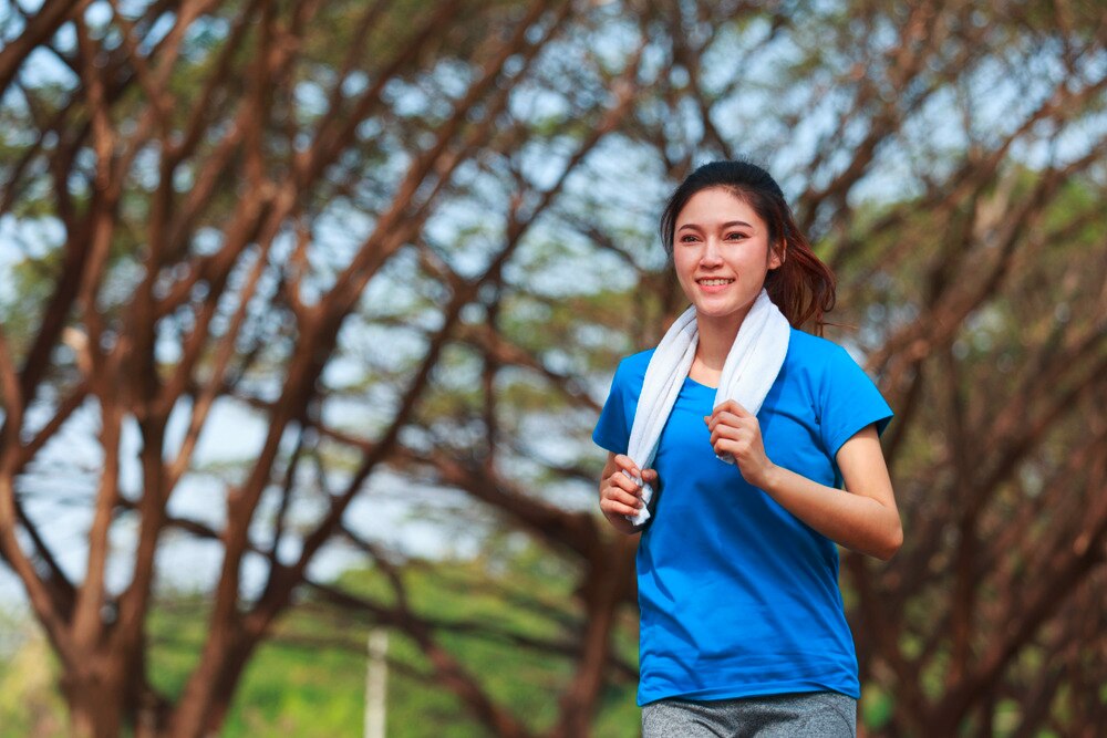 Woman in a blue shirt jogging outdoors.