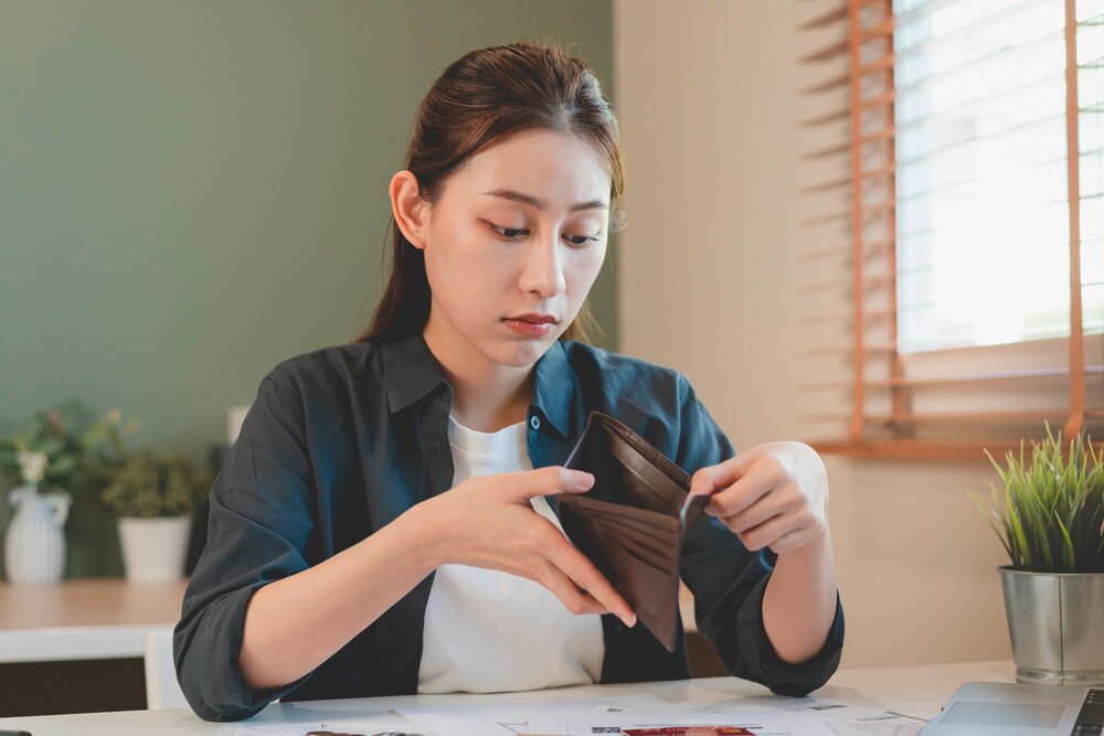 Woman looking at an empty wallet.