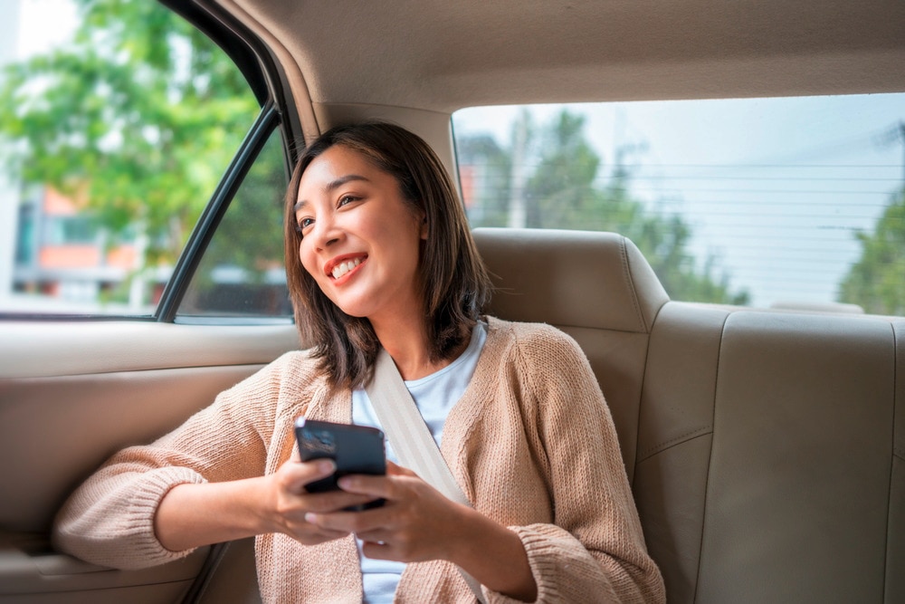 Relaxed Asian woman sitting in the backseat of a car.