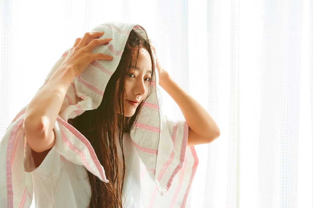 Woman drying her wet hair with towel.