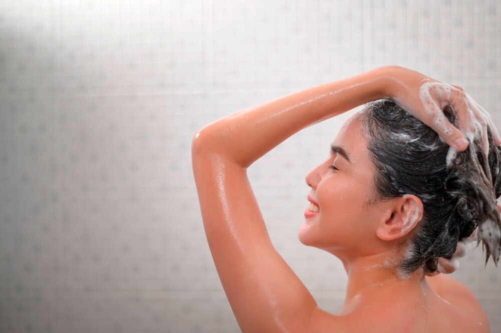 Woman washing her hair with shampoo in the shower.
