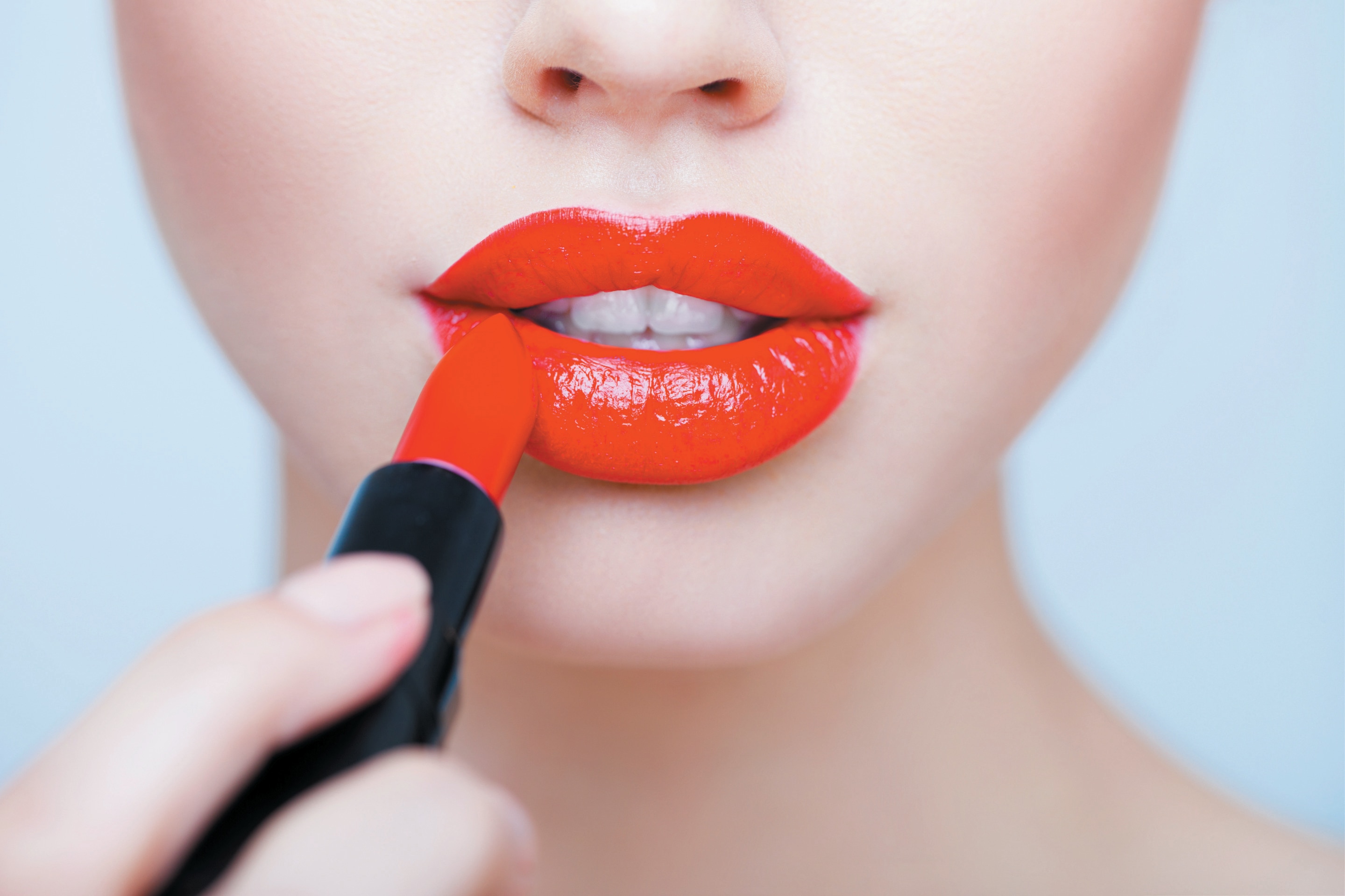 Woman applying red lipstick closeup