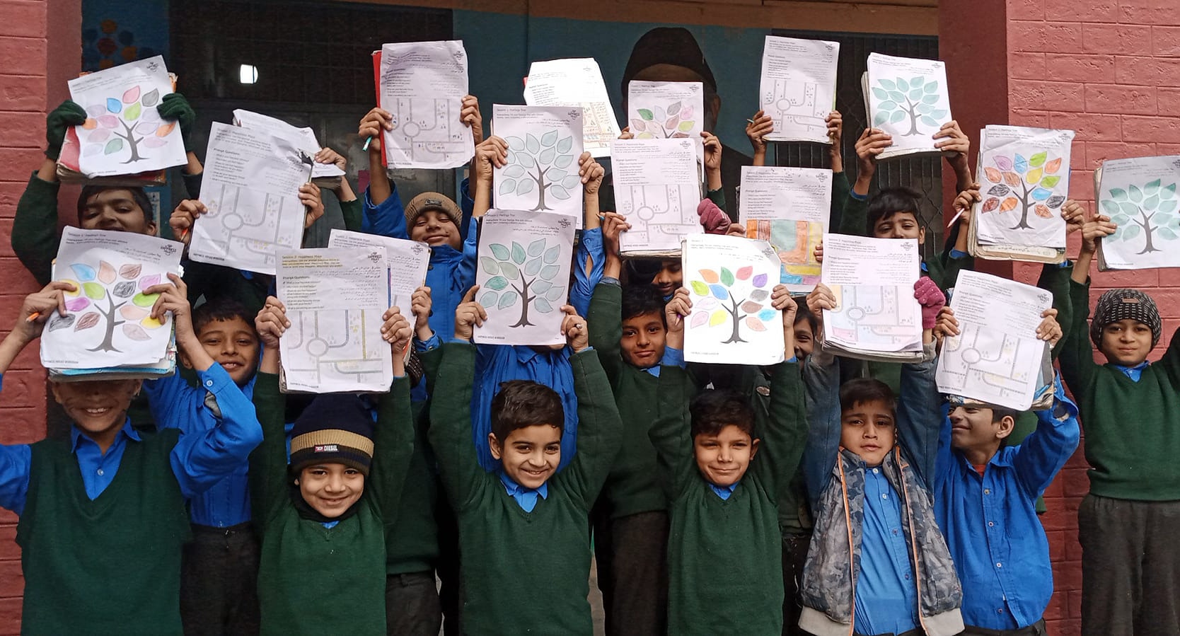 A group of students holding up their happiness project workbooks