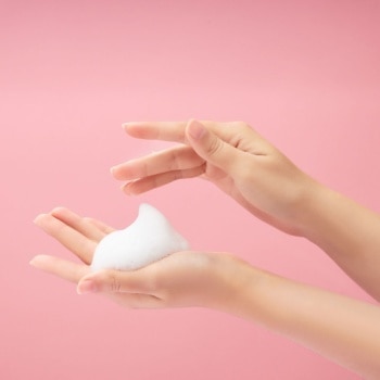 hướng dẫn cách thực hiện double cleansing đúng chuẩn lớp bọt trắng trên lòng bàn tay người phụ nữ trên nền hồng