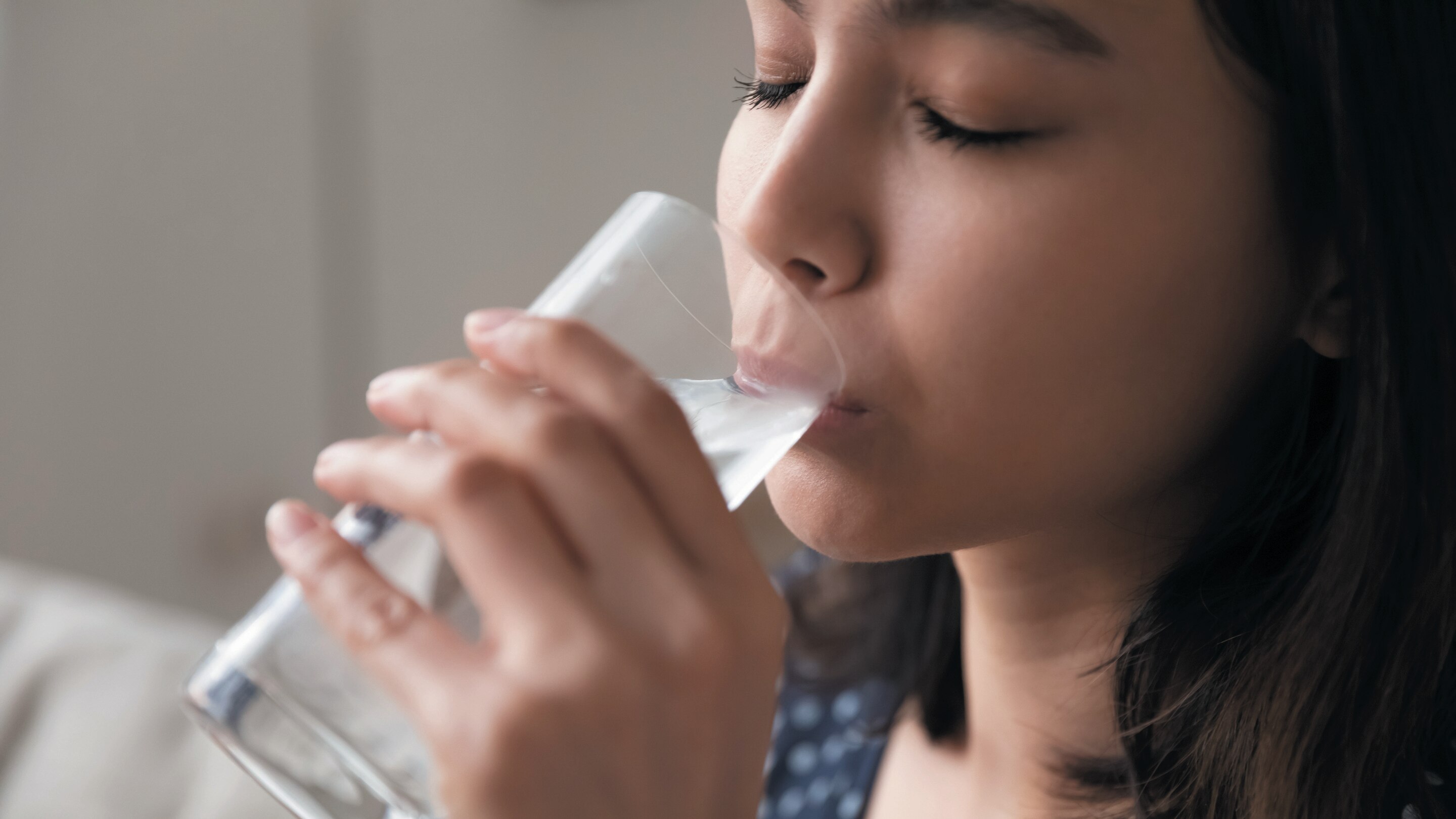 A woman drinking water with eyes closed