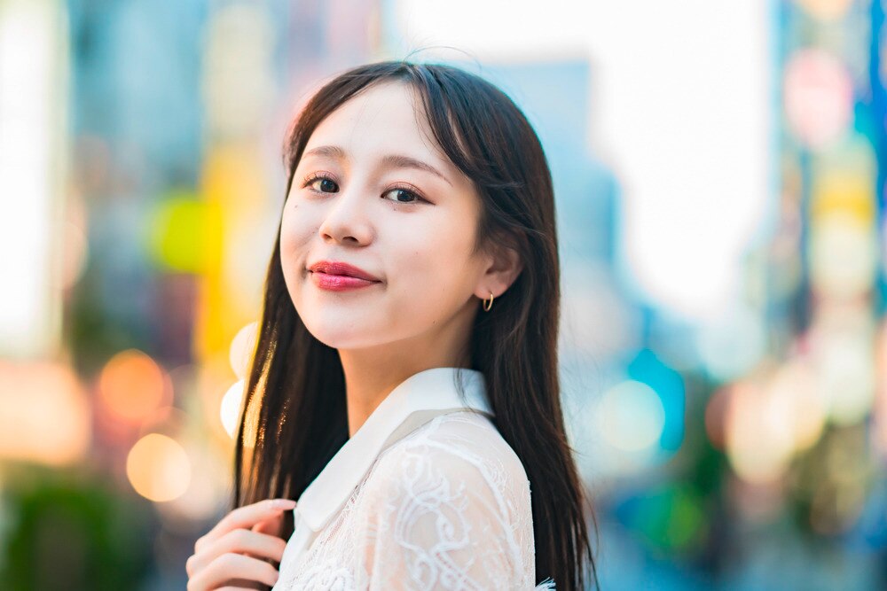 A portrait of smiling woman with long hair, city background.