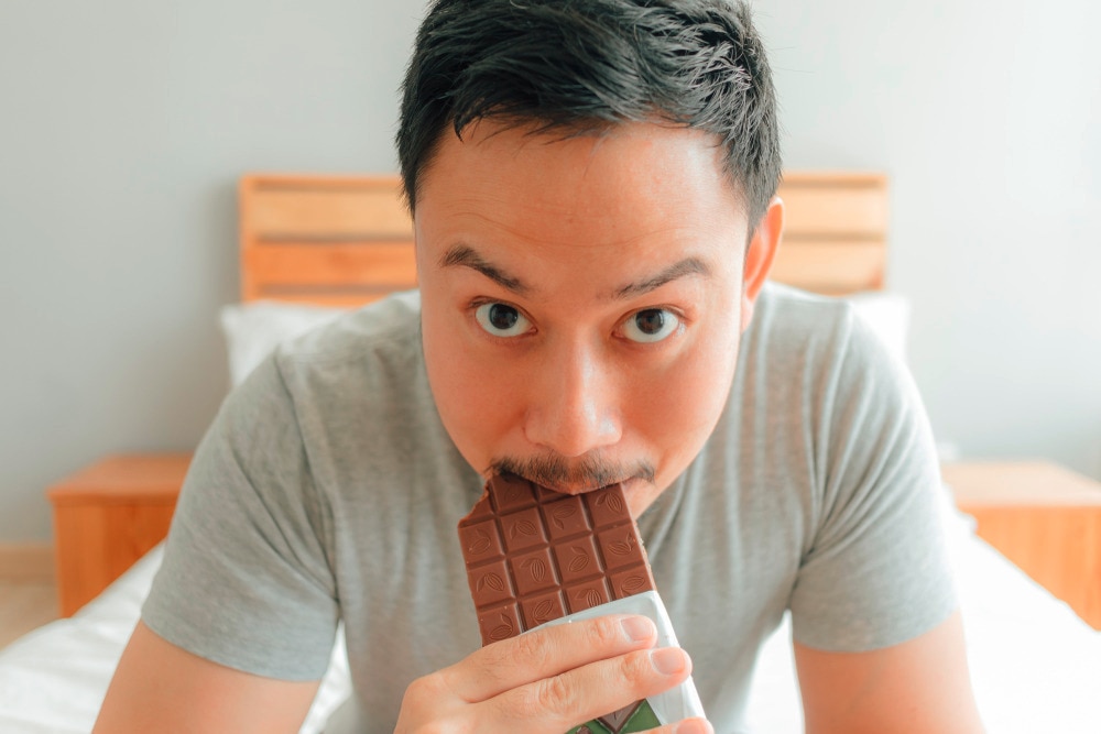 Man eating chocolate bar and staring at the camera.
