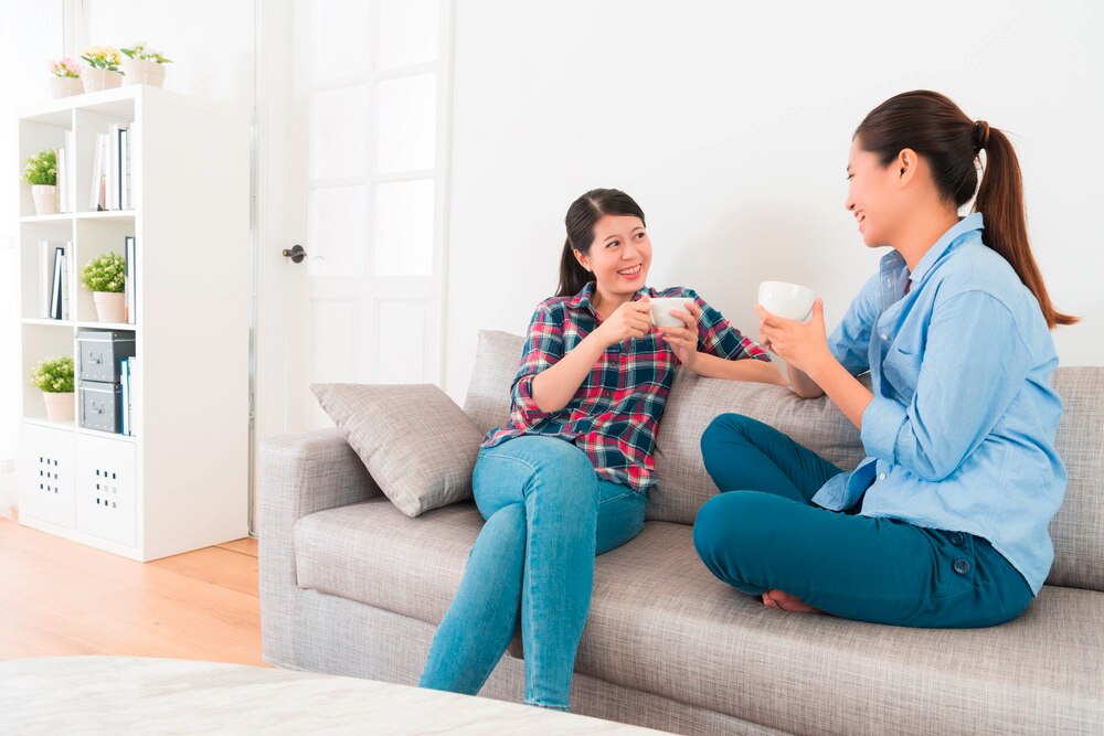 Asian friends drinking tea on the sofa.