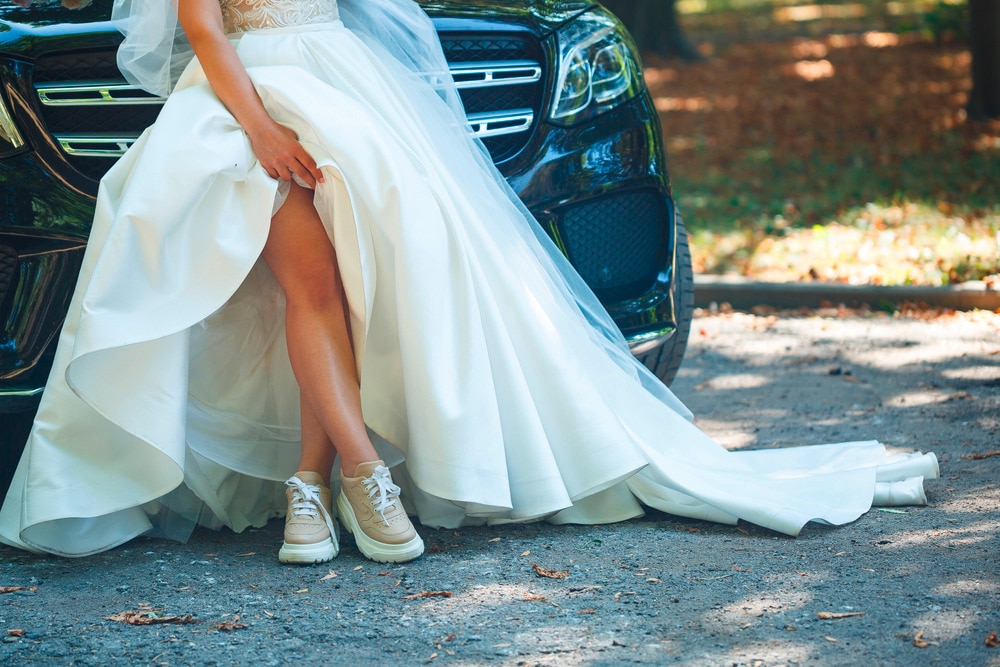 Cropped shot of a bride’s skirt wearing sneakers.