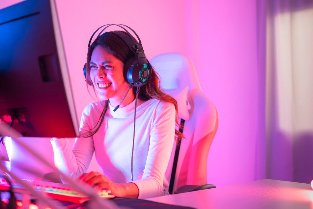 Woman with a headphone on playing games on a computer.