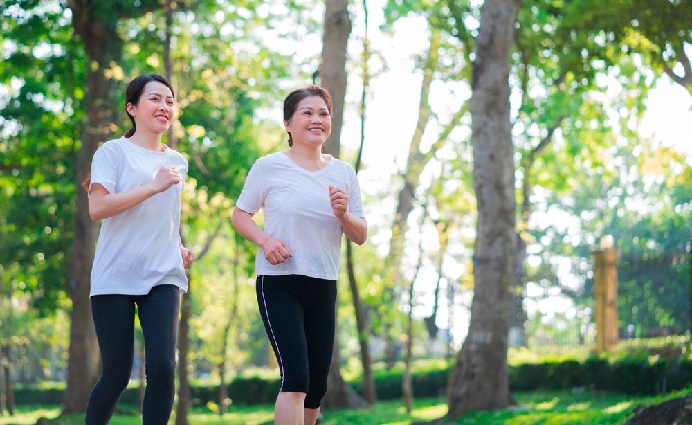 Asian mother and daughter jogging together at a park.