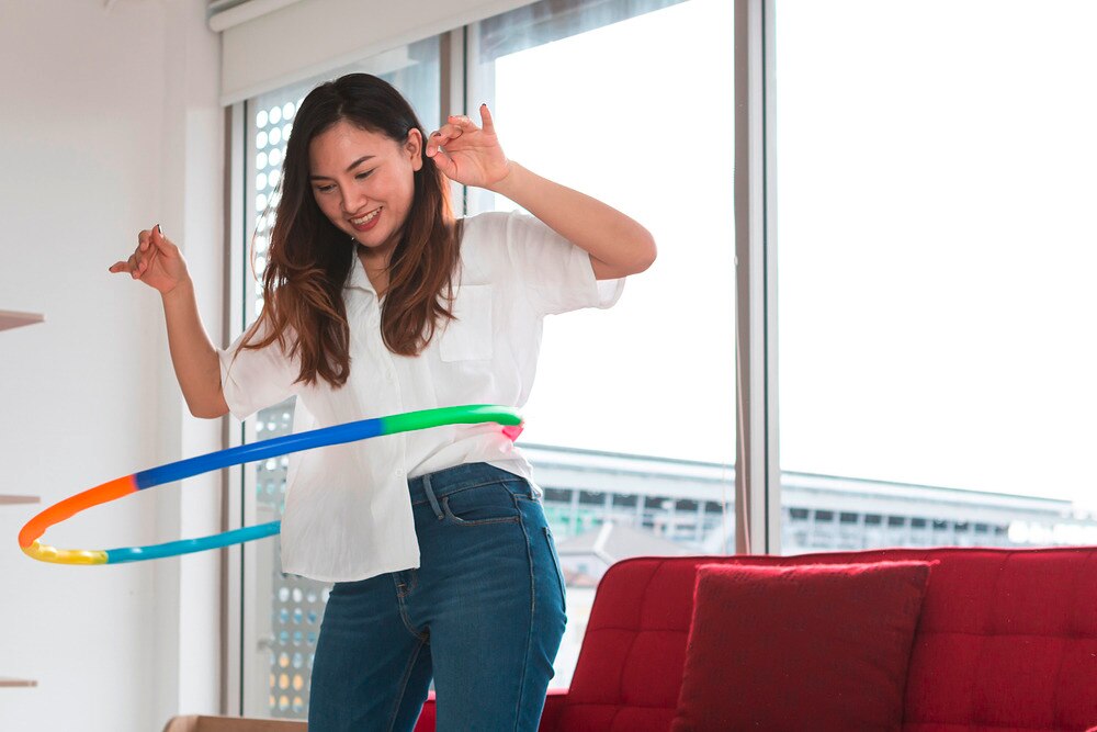 Woman playing hula hoop in the living room.