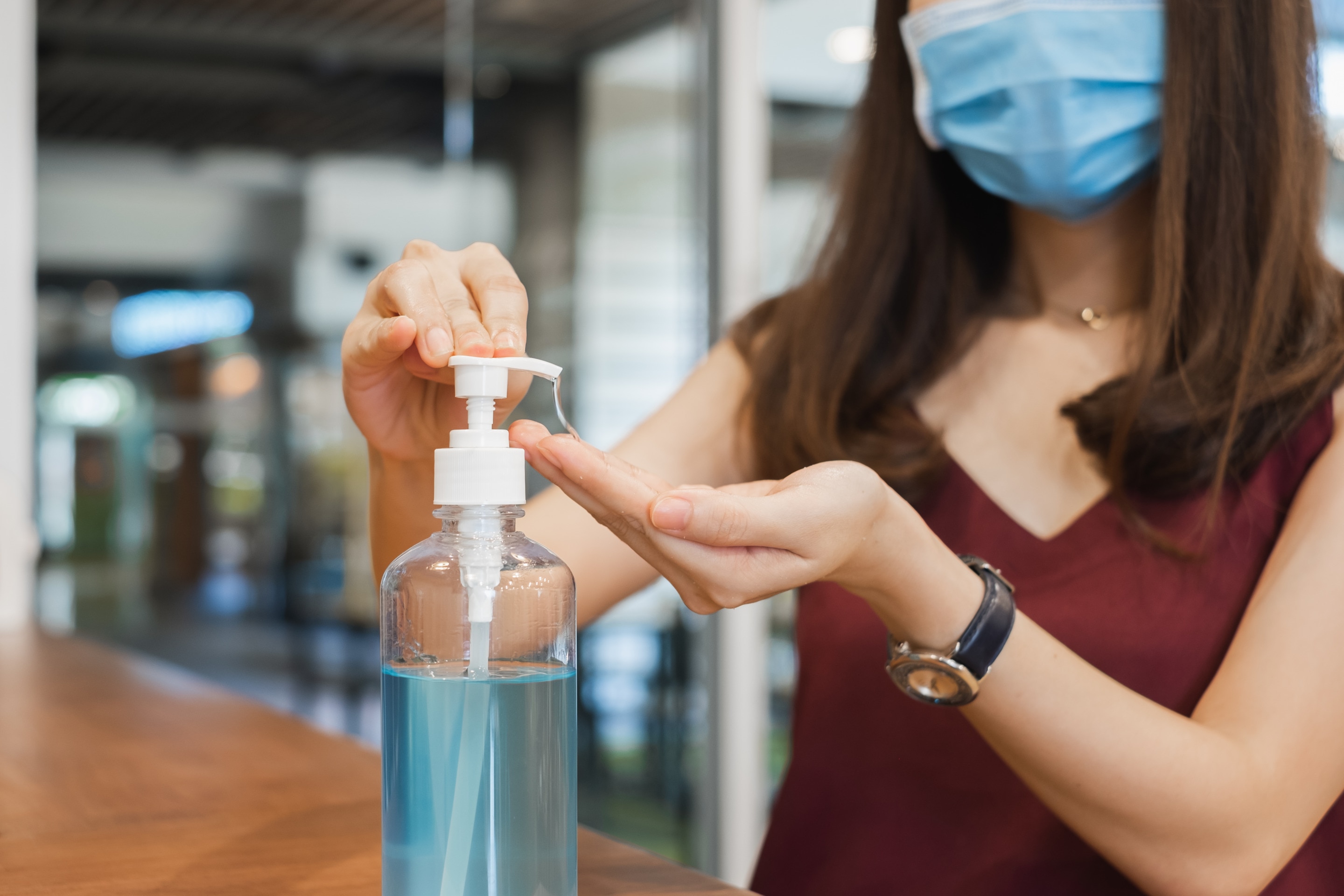Asian woman wearing face mask sanitizing hands