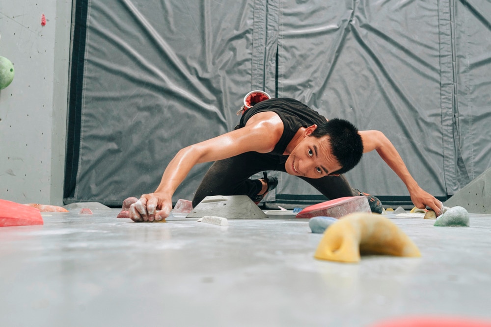 Asian man wall climbing.