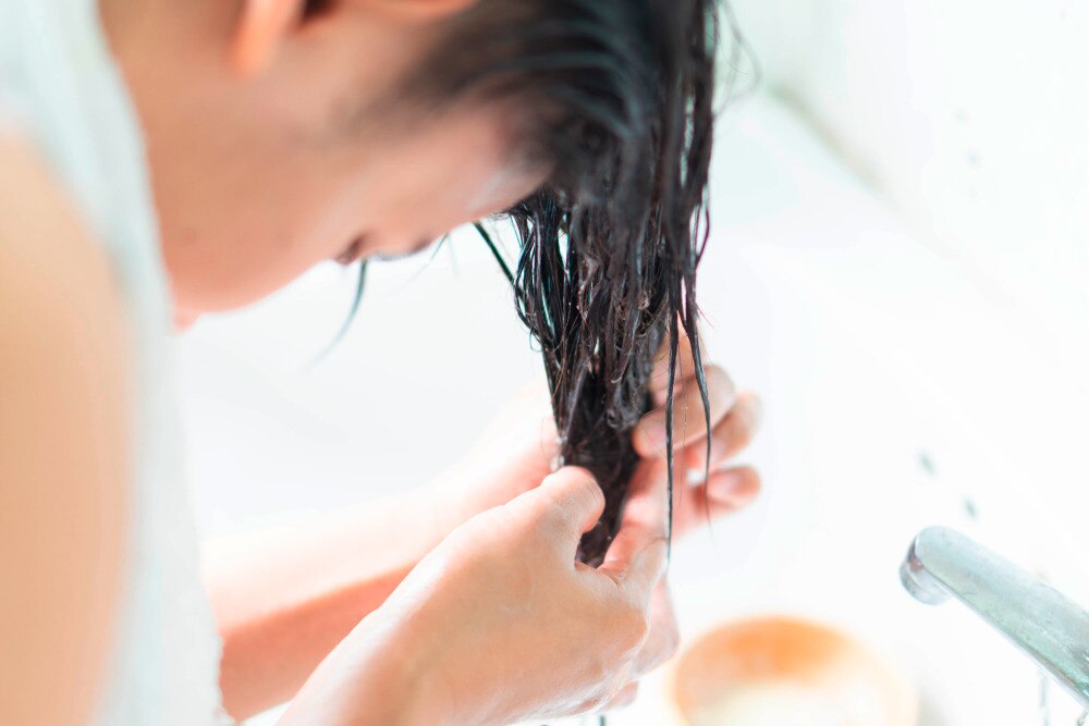 Woman applying conditioner on wet hair.