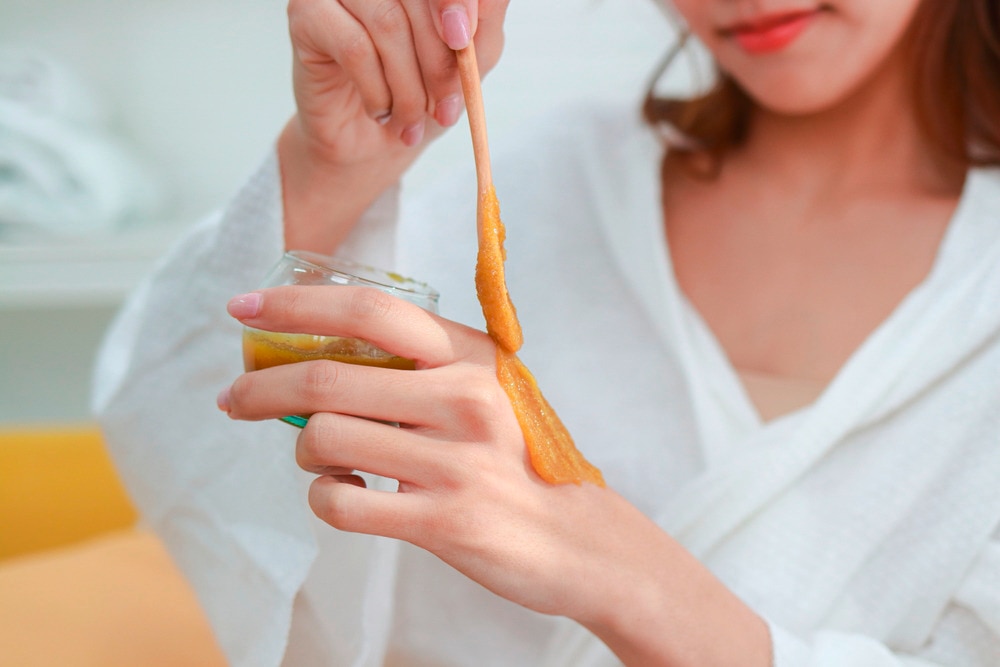 Woman applying turmeric paste on hand.