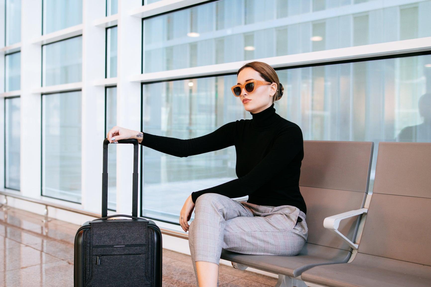 mujer sentada con maleta y gafas