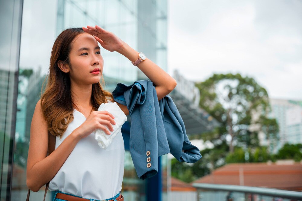 Asian woman overheating in warm climate.