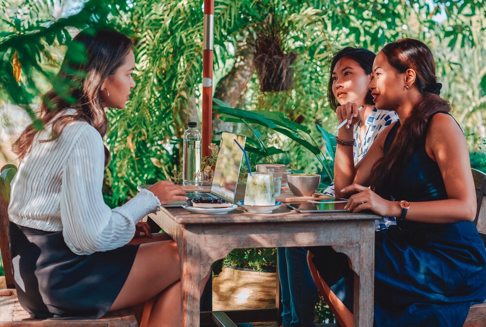 Asian female coworkers meeting over coffee.