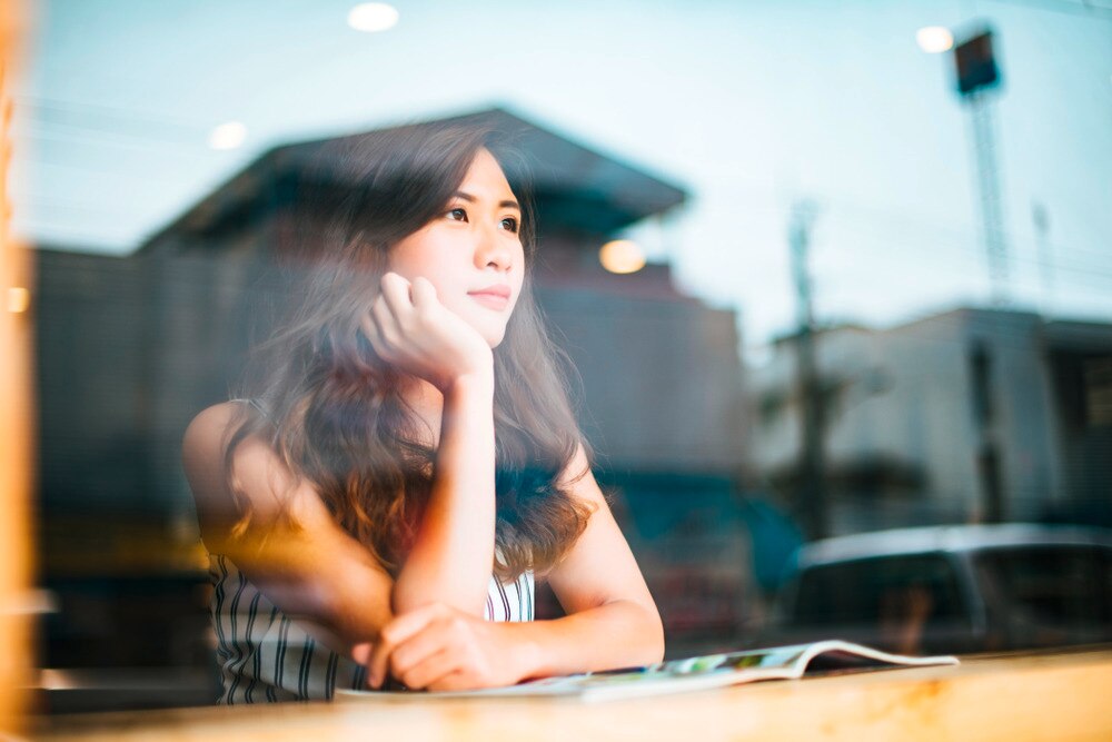 A portrait of woman looking out the window while sitting at a cafe.