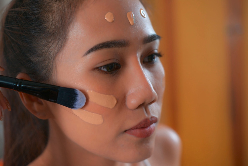 Asian woman applying foundation