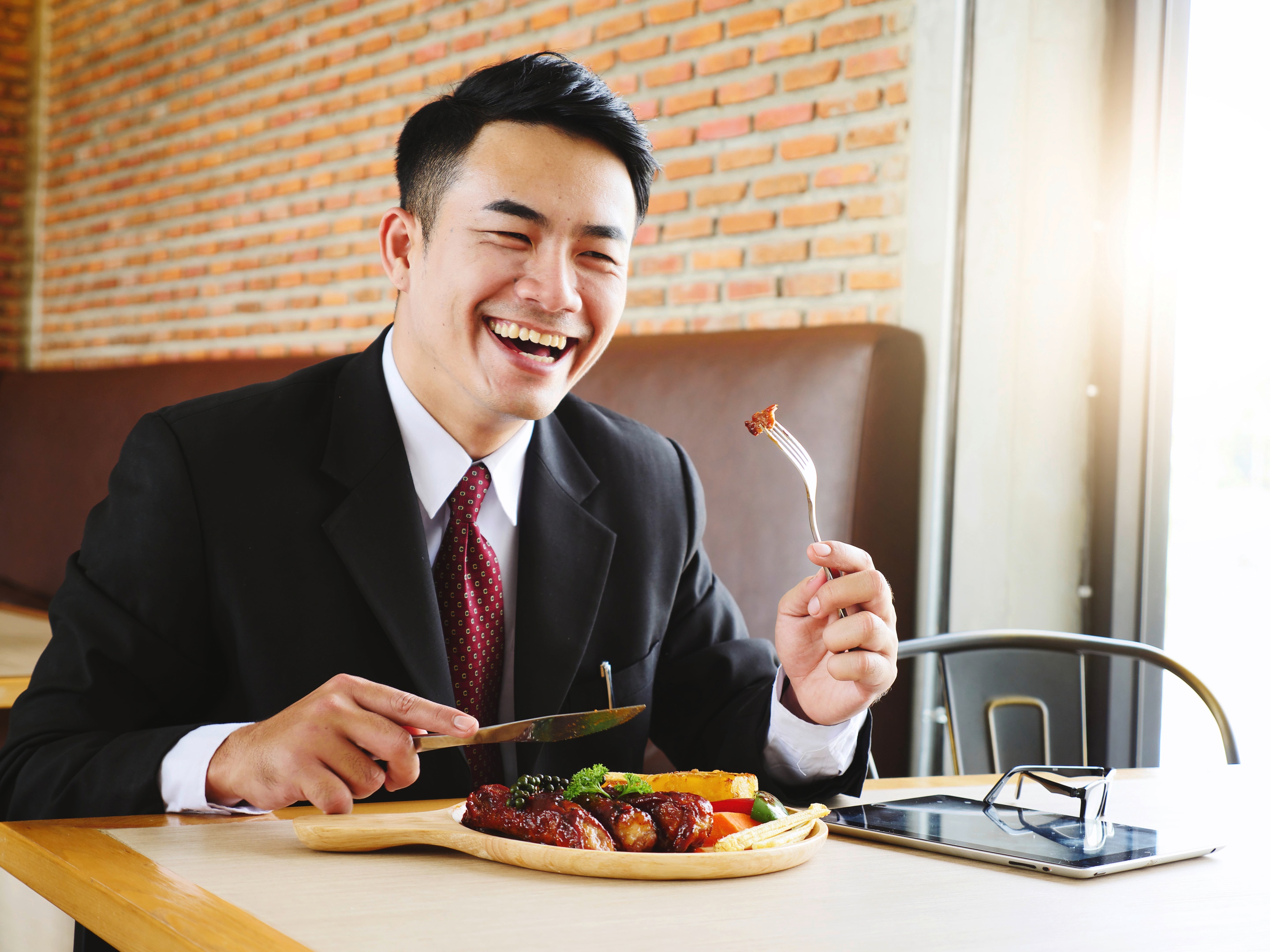 Asian man wearing a black suit and eating meat