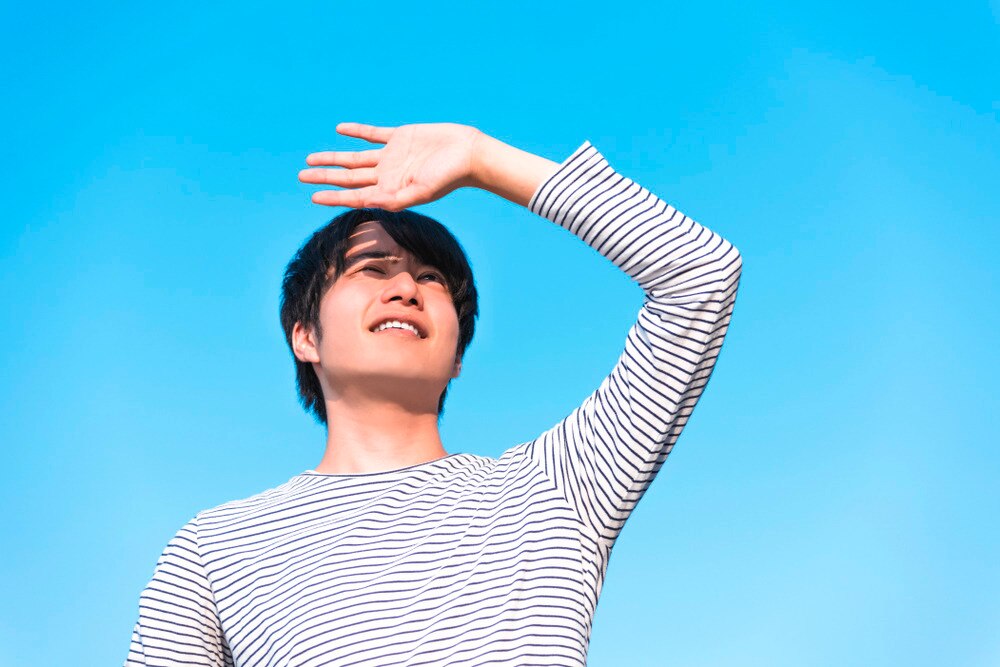 Man covering his eyes from the sun with his hand.