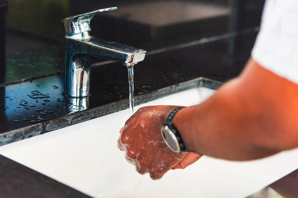 Man washing his hand in the sink.