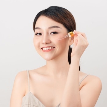 Asian woman applying serum