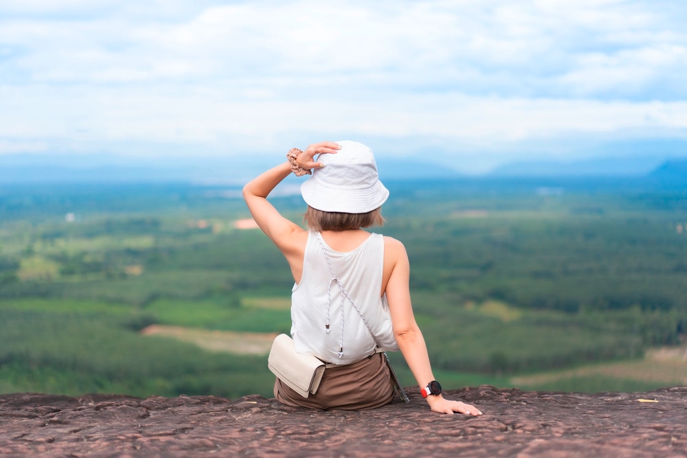 Back of an Asian woman wearing a white bucket hat looking at view. 