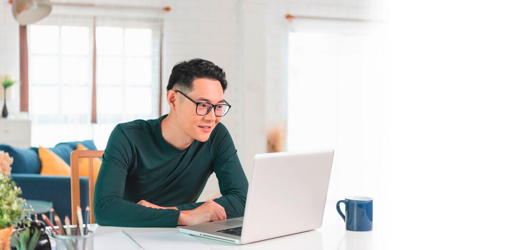 Asian man having a Zoom meeting on laptop.