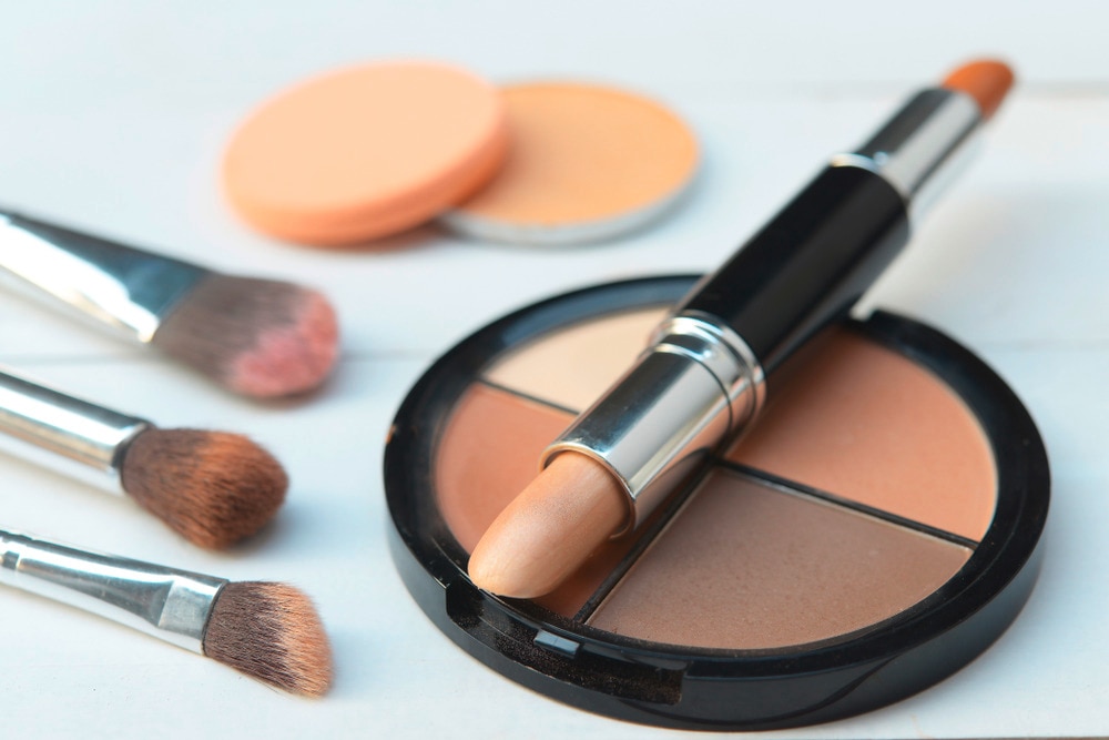 A portrait of contour stick, contour and bronzer palette, makeup brushes and sponges.