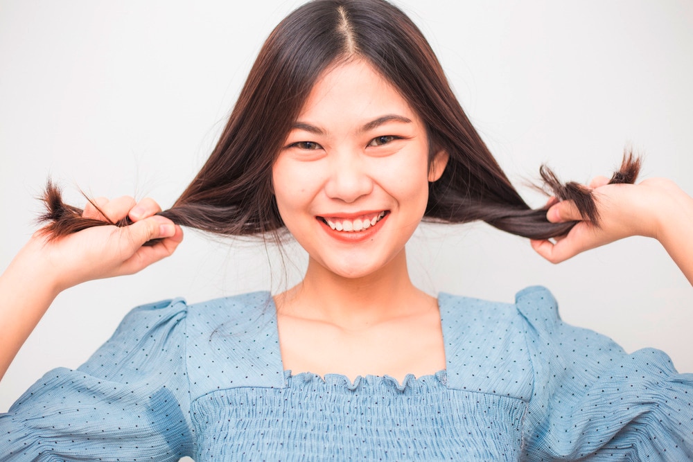 Smiling woman twisting and playing with her hair.