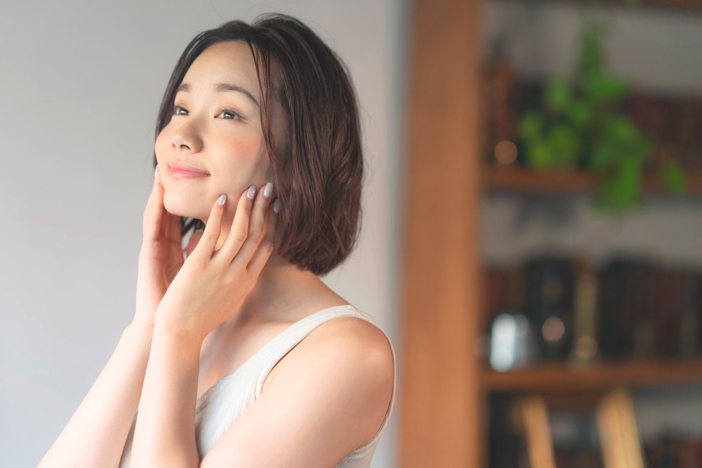 Smiling woman touching her face with both hands.