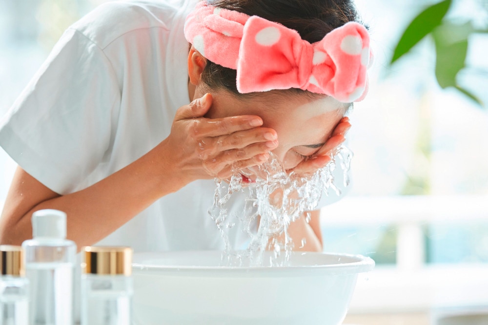 Woman splashing her face with water.