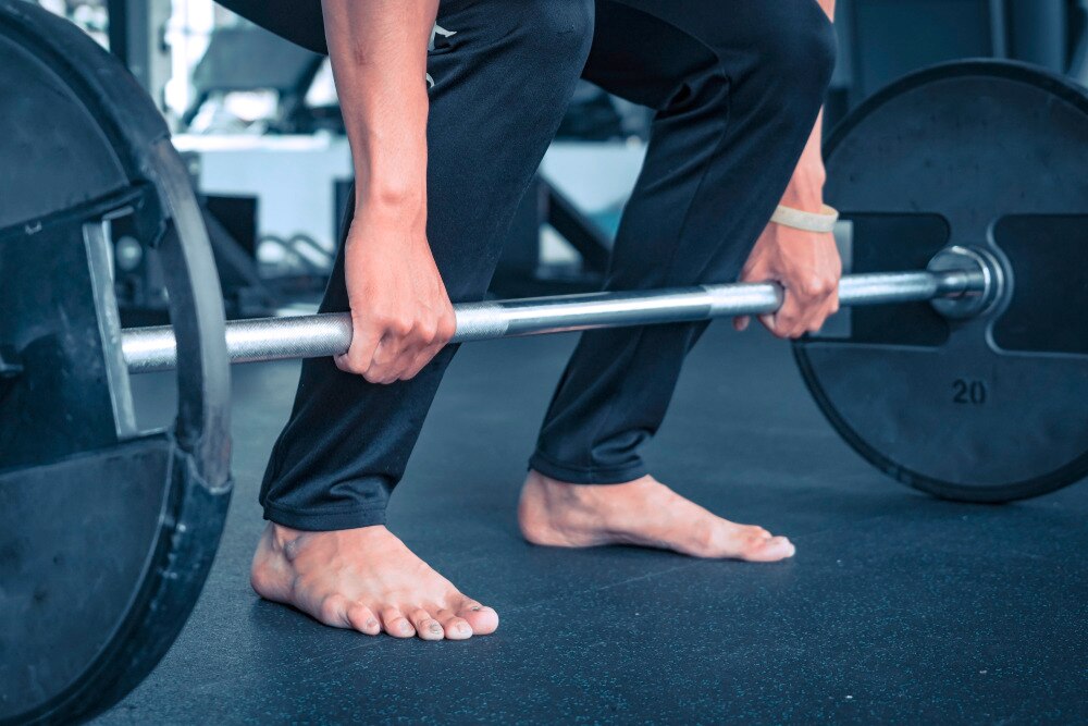 Man doing deadlift barefoot at the gym.