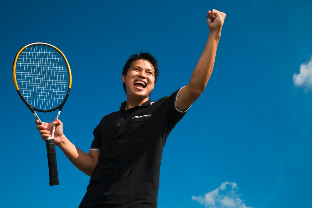 Asian man in black shirt playing tennis