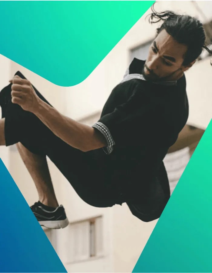 Un patineur avec une chemise noire faisant un demi saut périlleux dans les airs.